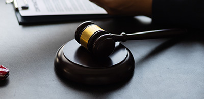 gavel resting on a round base with a blurred background showing a clipboard and hand representing justice and the legal system five important legal concepts