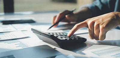 person using a calculator for financial calculations with documents and graphs on the table involving number six analysis