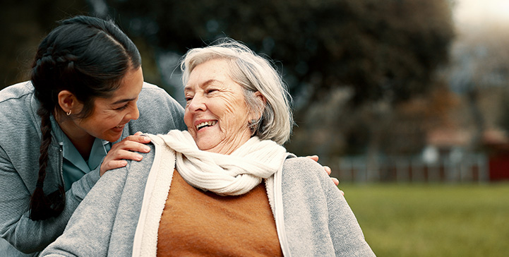 two women sharing a joyful moment outdoors the elderly woman is smiling while the younger woman looks at her fondly connection and care in their eyes seven moments of happiness